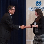 Doctor Smart shaking hands with an award recipeint in a grey and black striped dress